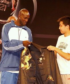 KG receives a traditional Chinese shirt from a fan during a press conference in Shanghai